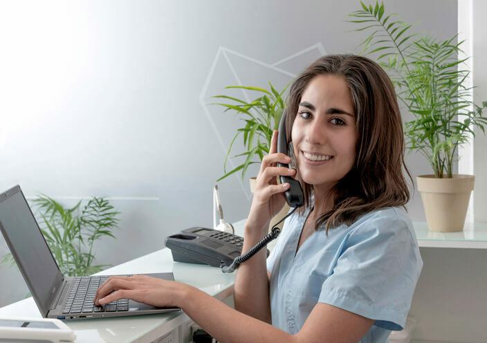 A female medical assistant manning the phone at a clinic after her medical office assistant training