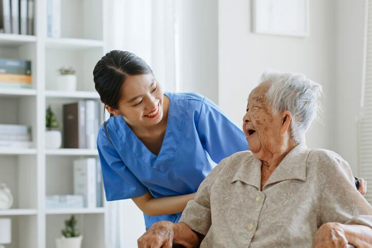 A health care aide training grad speaking with an elderly patient 