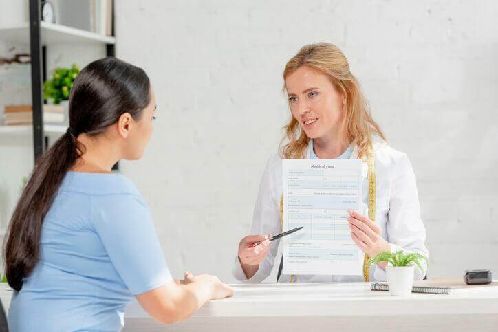 A career college graduate helping a patient with a medical form 