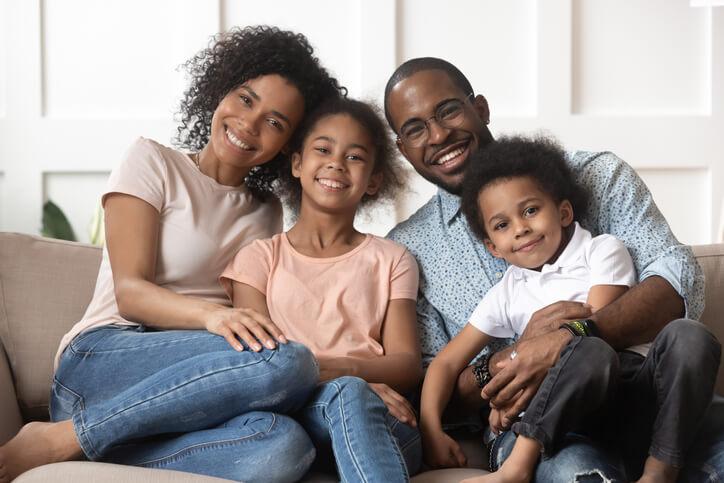 Smiling family relaxing on a couch at home after immigration administration training 
