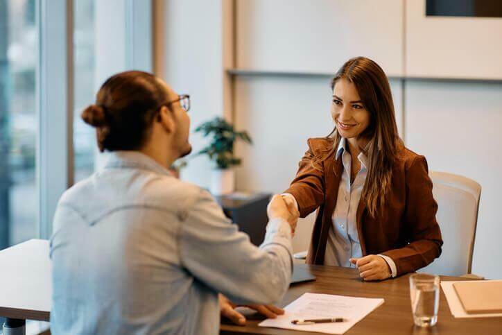 A business administration training grad shaking hands with a candidate