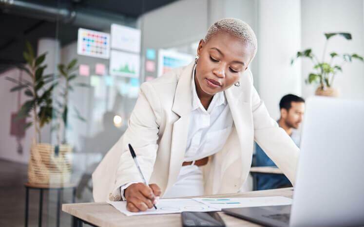 A business administration training grad working standing at a desk