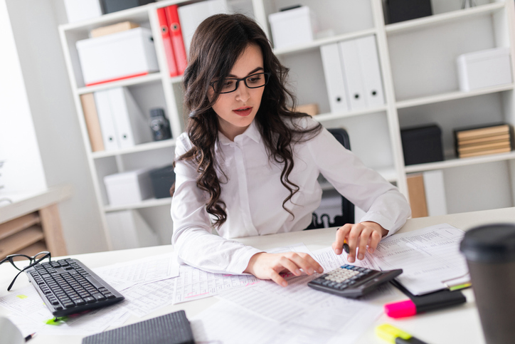  A focused female payroll assistant working in an office after completing her accounting assistant training