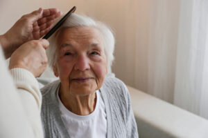 A healthcare aide combing a client’s hair 