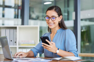 A smiling female web developer testing a website on mobile after completing her web developer training