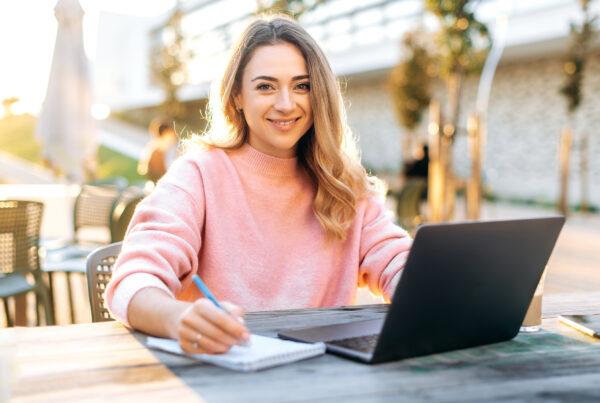 A smiling female educational assistant working on a computer at a school