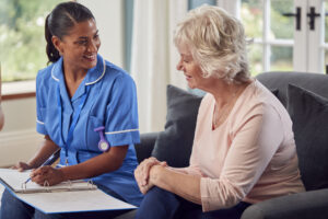 A smiling female Community Service Worker interacting with an elderly female client