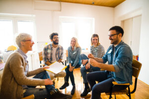 A female community, service and addictions worker interacting with a group of clients in a session