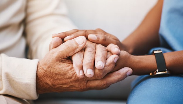 A graduate of a health care aide diploma program comforting a patient