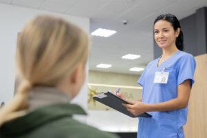 A medical office assistant welcoming patients at a clinic reception