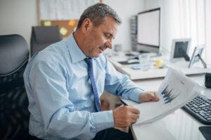 A business administrator reviewing financial reports and schedules in a small office, supporting small business operations