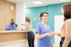 A medical office assistant greeting a patient at a specialty clinic reception