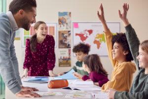 An educational assistant collaborating with a classroom teacher while supporting a student activity