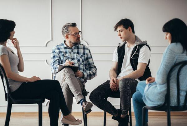 An addiction worker facilitating a supportive conversation between family members in a counselling setting
