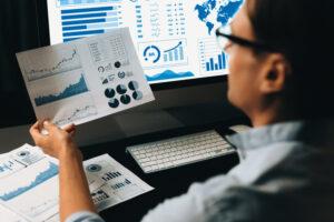 A Manager comparing dashboard metrics and a written report to support data-driven decision-making in business management