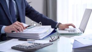 Professional reviewing accounting records and audit files on a computer